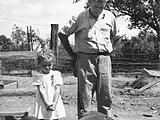 Patsy Cahan with her grandfather Thomas L. Eatherton and his pigs, c. 1942.